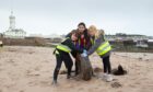 Pupils unearth an old tyre on the beach at Inchcape. Image: Paul Reid
