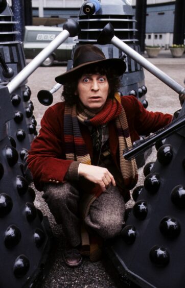 Doctor Who actor Tom Baker poses with his fictional enemy the Daleks, circa 1975