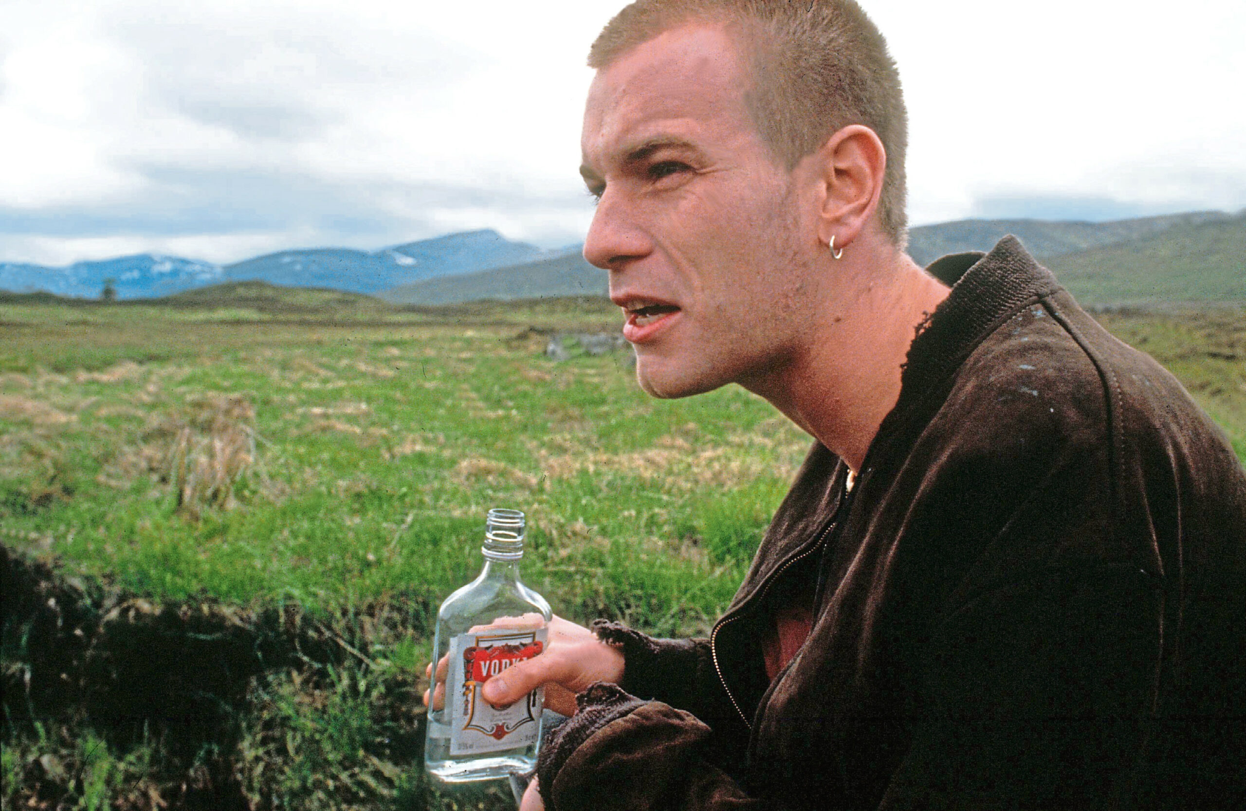 Ewan McGregor as Mark Renton holding a bottle of vodka in Trainspotting.