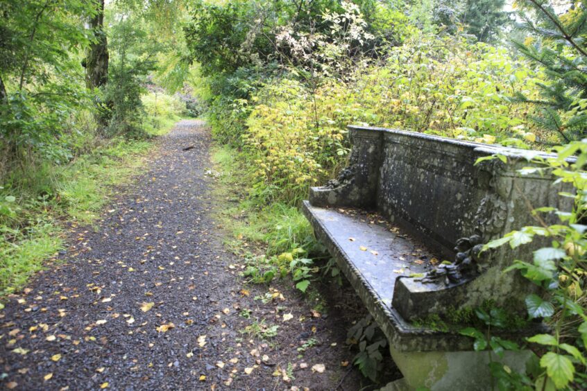 Stone bench next to path with autumn leaves at Battleby House.