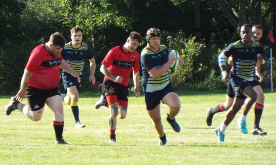Owen (holding the ball) spends his time off work playing rugby.