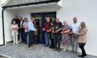 Michael Fotheringham (blue shirt, centre) cuts the ribbon on the new Johnshaven Hall annexe. Image: Supplied