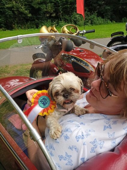 Geraldine Miller and dog Poppy seated in motorcycle side car.