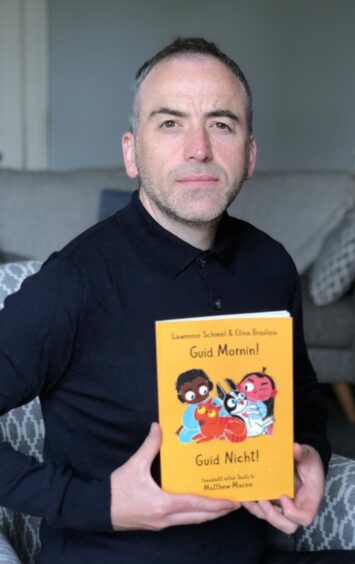 Matthew Mackie holding a copy of his book