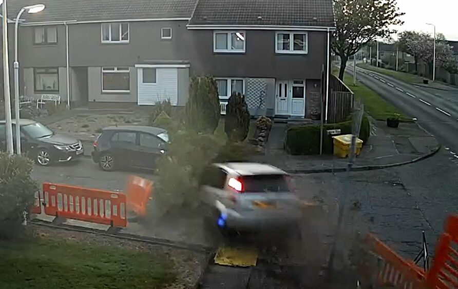 A still from the video shows the car ploughing through the Fife garden, with a bush on its bonnet.