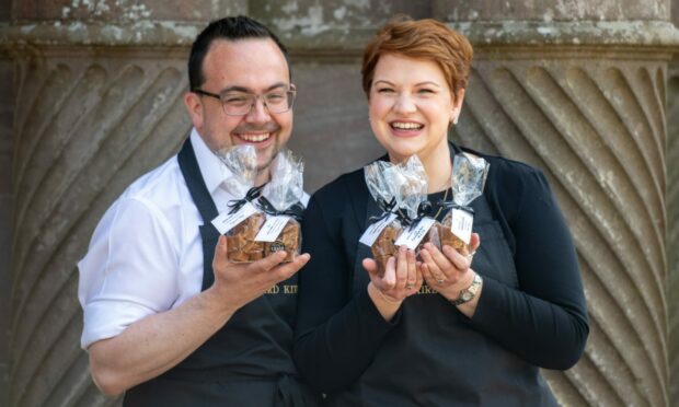 Scott and Stephanie holding bags of Kinnaird Kitchen fudge outside the caste.