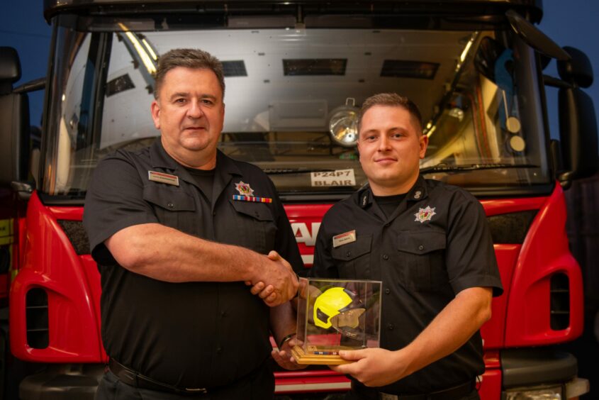 Chic Scrimgeour and Watch Commander Paul Smith shaking hands in front of an engine at Blairgowrie fire station