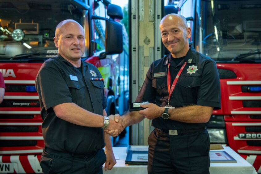 Alan Smith receiving long service medal from fire chief Jason Sharp at Blairgowrie fire station.