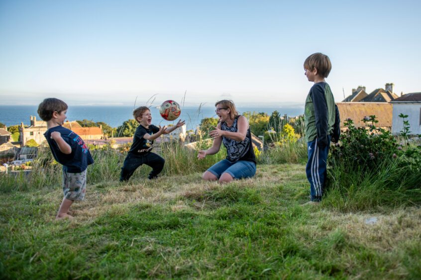 Mum Louise, owner of Grain and Sustain, playing with her three young boys in their garden.