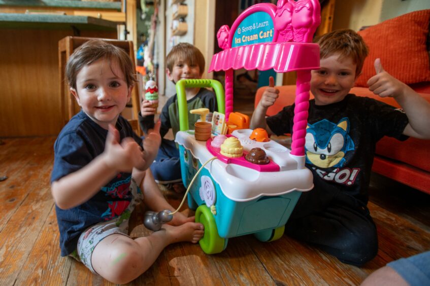 Louise's three young boys, posing with one of their second hand toys. 
