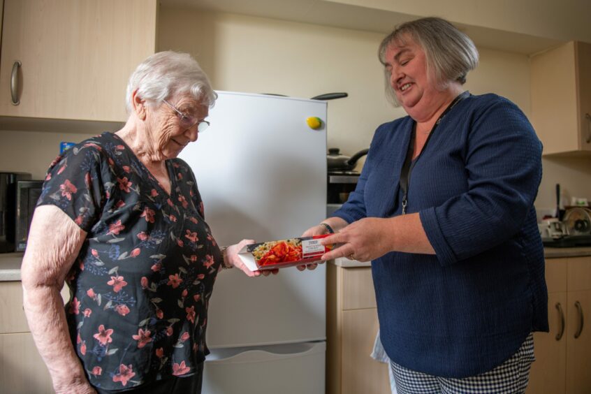 Heather Fletcher helping Marjorie Bridgwood put away her shopping