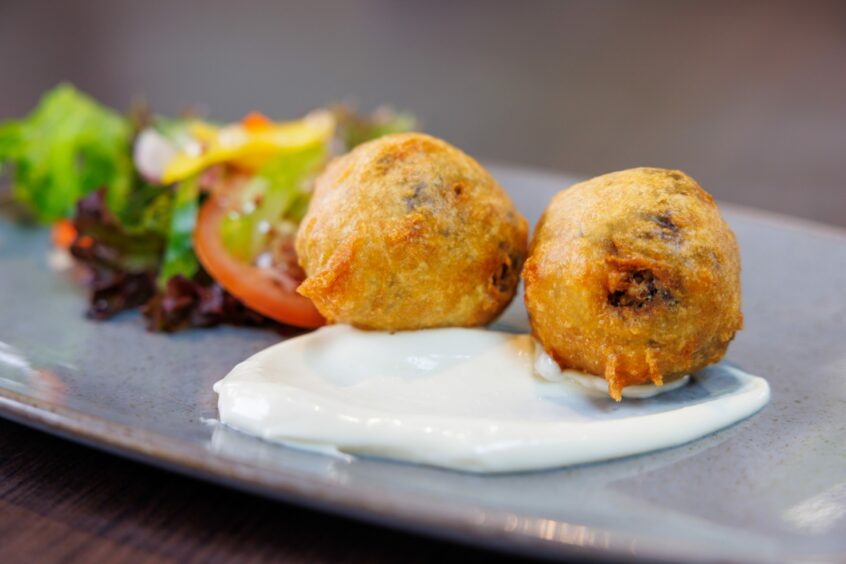 Two deep fried haggis bon bons sitting on top of whisky mayo.