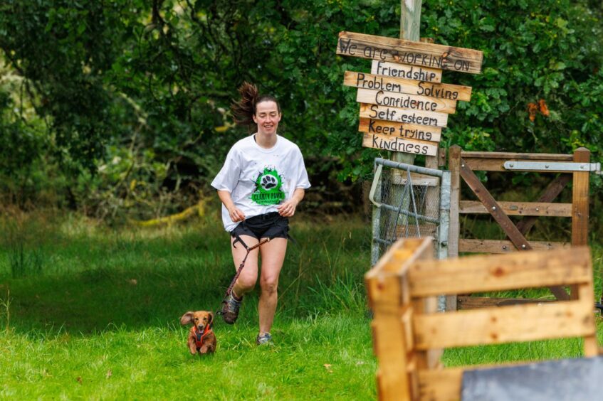 Girl running with sausage dog at Auchingarrich.