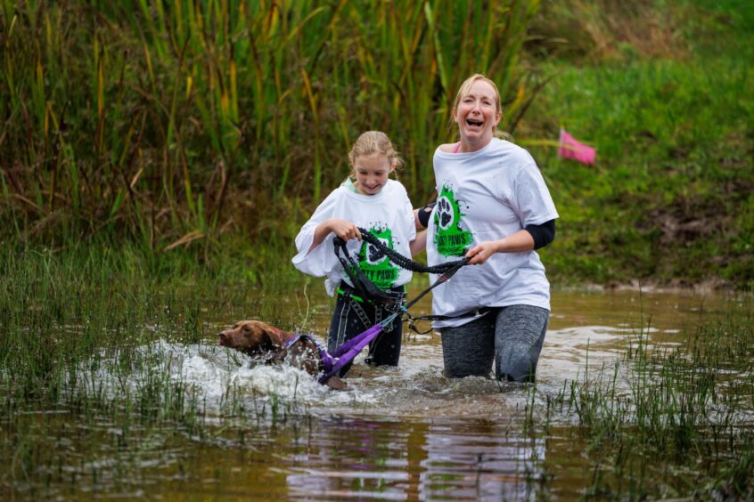 Cat McInally with daughter Chloe, 10, and Luna the spaniel wading through the river at Auchingarrich