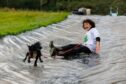 Morag Lindsay sliding down a water slide at Auchingarrich wildlife park with her spaniel.