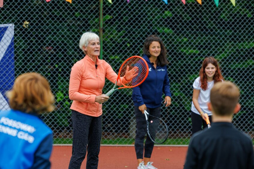 Judy Murray holding tennis racquet and talking to children while Alessia Palmieri looks on.