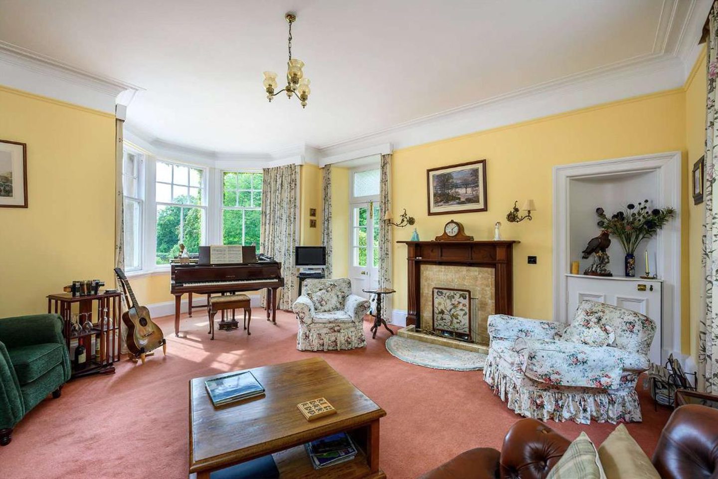 The sitting room, which is painted yellow and also has bay windows.