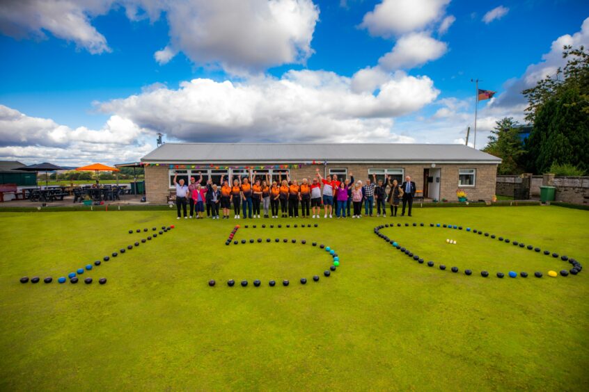 Players on the green at Dunning Bowling Club with bowls laid out in the shape of the numbers 1 5 and 0 