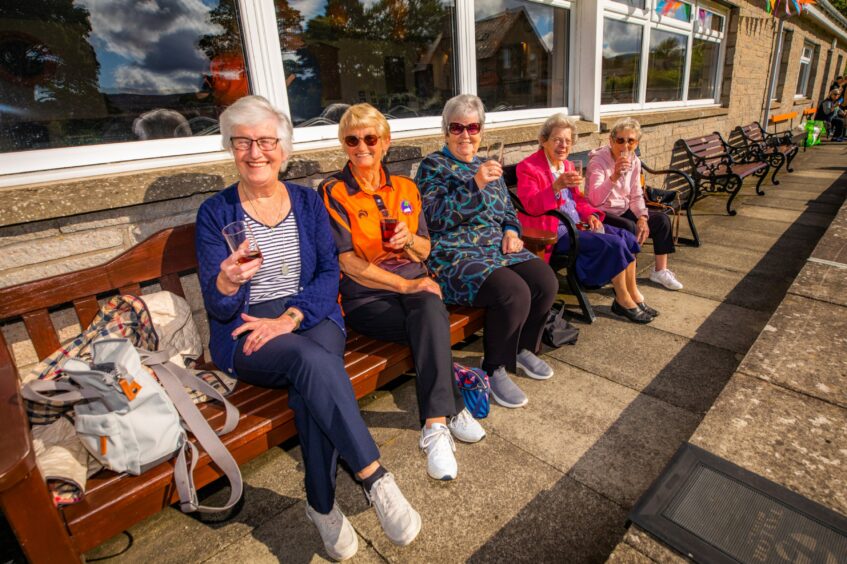 Etta Gardiner, Audrey Smith, Maureen Silverman, Nan Ross and Cathy Faulkner enjoying a cold drink on benches outside the Dunning Bowling Club clubhouse.