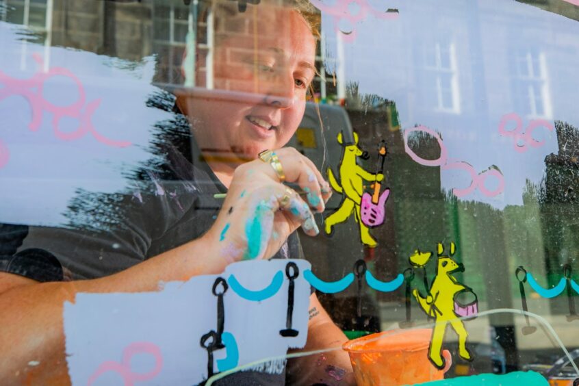 Jaz Grady painting on shop window in Perth's St John street.