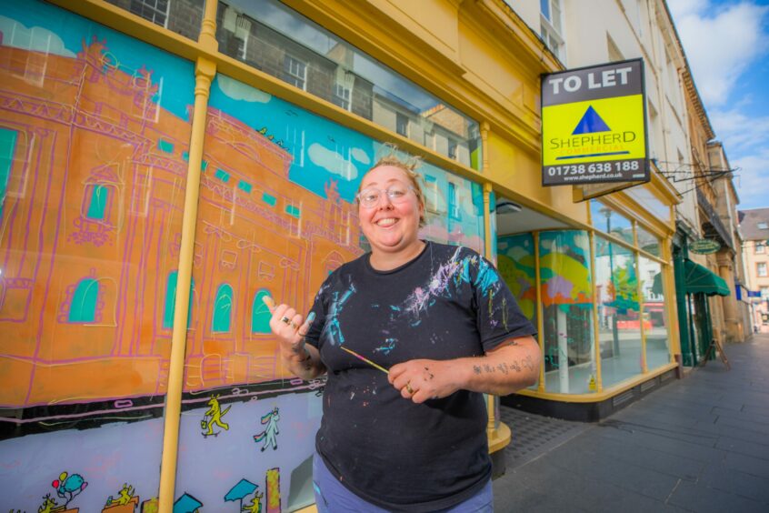 Jaz Grady outside Perth shop unit with her colourful illustrations on windows.