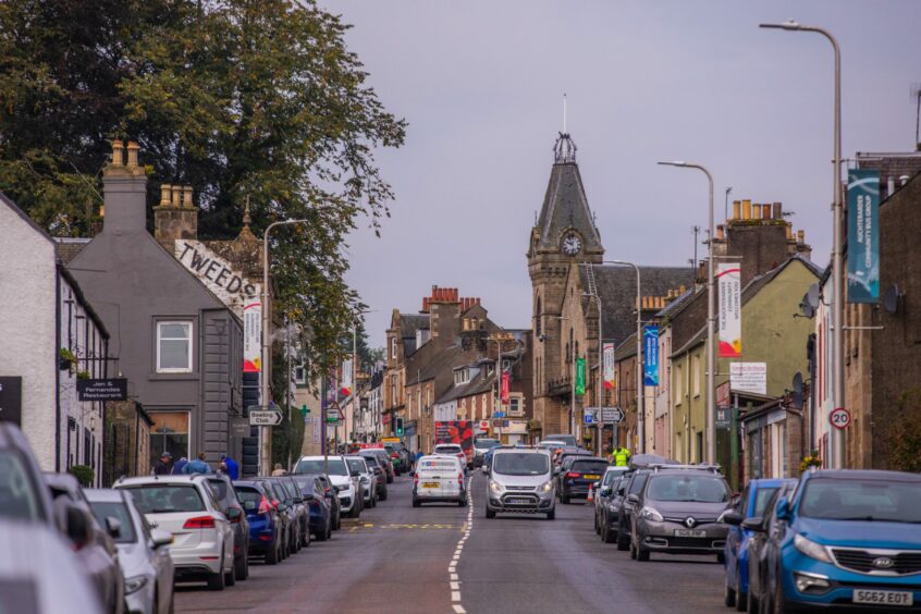Auchterarder High Street with cars parked in either side and traffic heading in both directions.