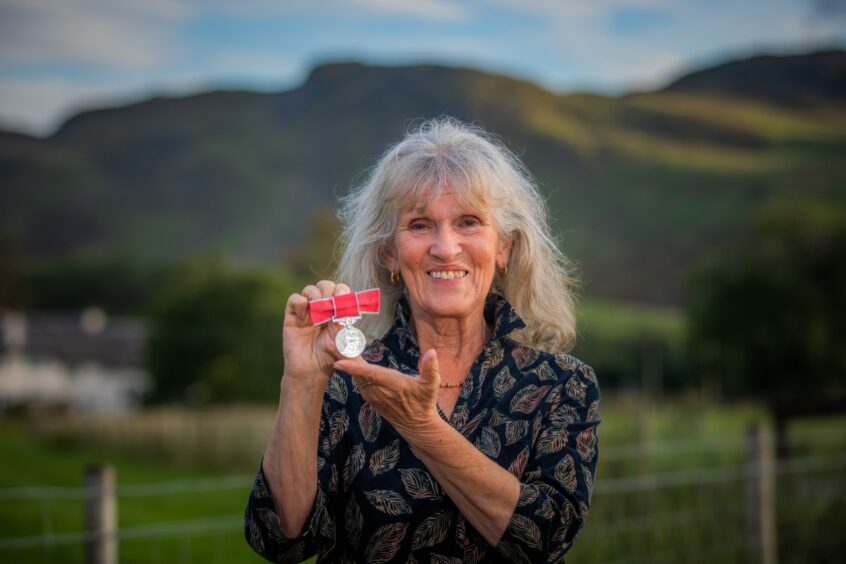 Jess Smith holding BEM surrounded by Sottish scenery.