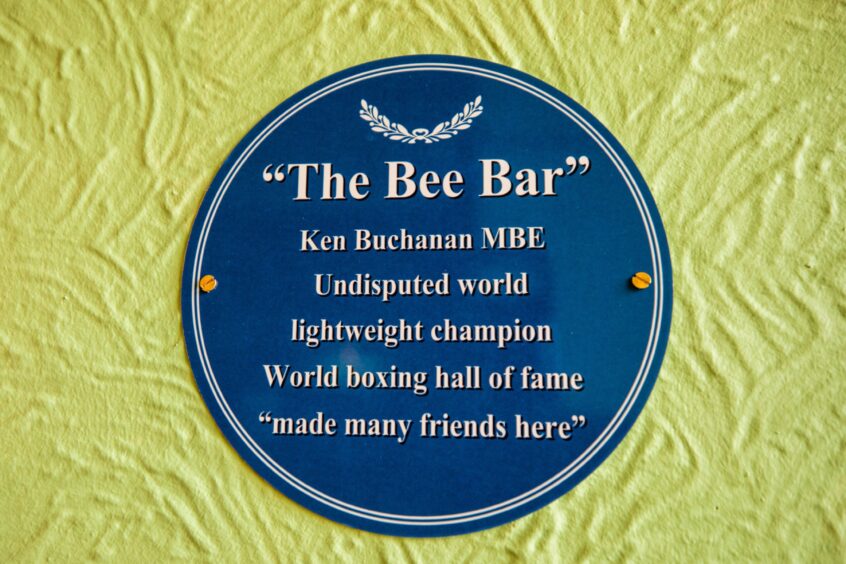Blue plaque which reads: 'The Bee Bar, Ken Buchanan, undisputed world lightweight champion, World boxing hall of fame, made many friends here''