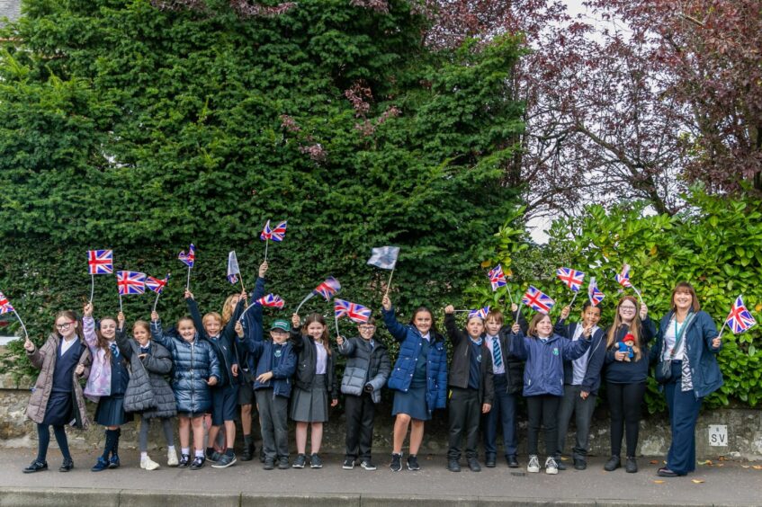 Children from Cleish Primary waving flags as they wait for the King in Kinross.