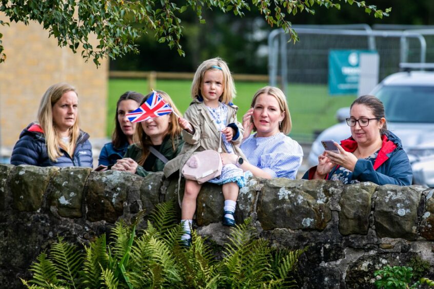 Group of women with little girl holding Union Jack flag on a wall