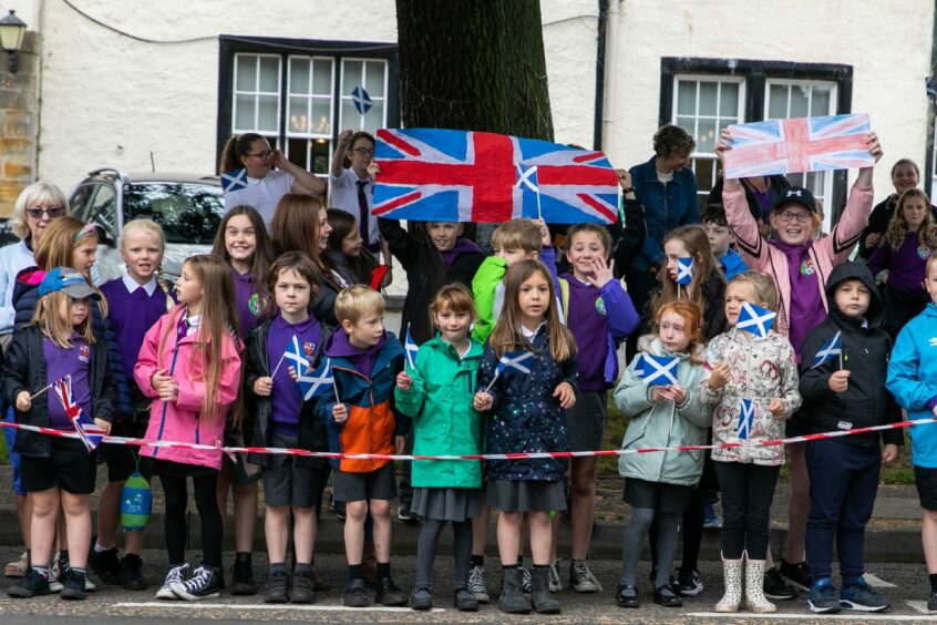Kinross Primary pupils on the pavement with flags
