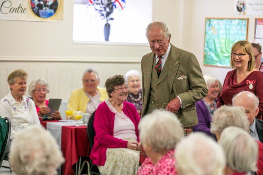 King Charles walking past tables with older ladies seated at Kinross Day Centre