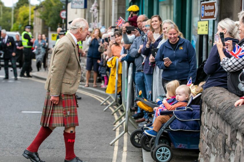 King Charles crossing the street to see children in push chairs