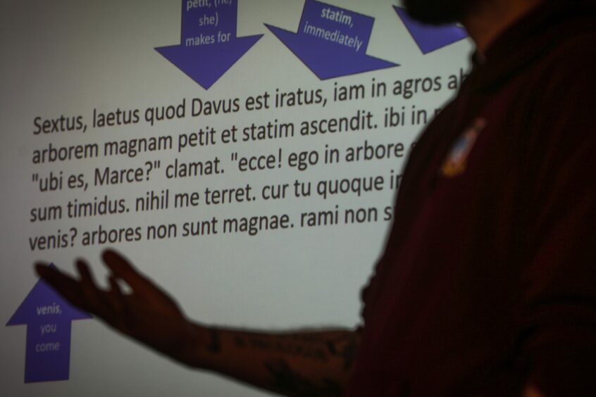 Latin text on screen at Monifeith High.