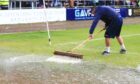 Dundee groundsman Brian Robertson sweeps rain from the Dens Park pitch in August. Image: David Young/Shutterstock