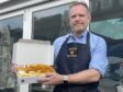 Gavin Murray of McKays Fish and Chip Shop holding a box containing fish and chips outside the shop.