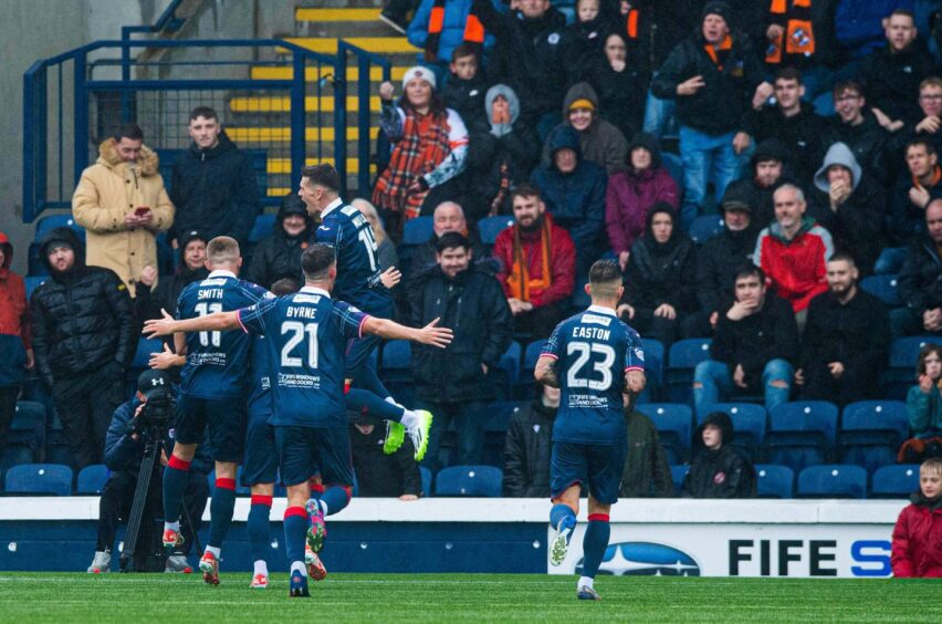 Raith Rovers players celebrate in front of Dundee United fans after Lewis Vaughan scores.