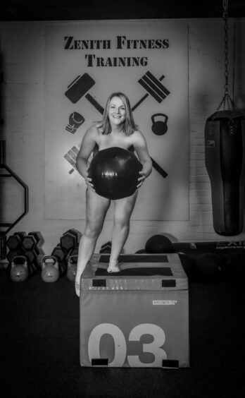 Naked woman holding a large gym ball