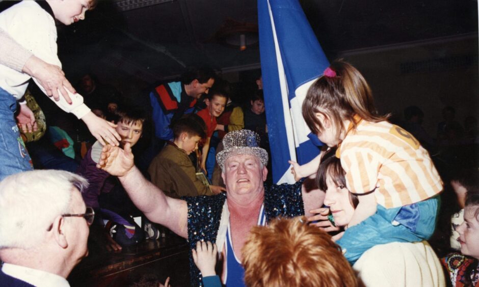 Big Daddy enters the Caird Hall in 1991 waving the Scottish flag. Image: DC Thomson.