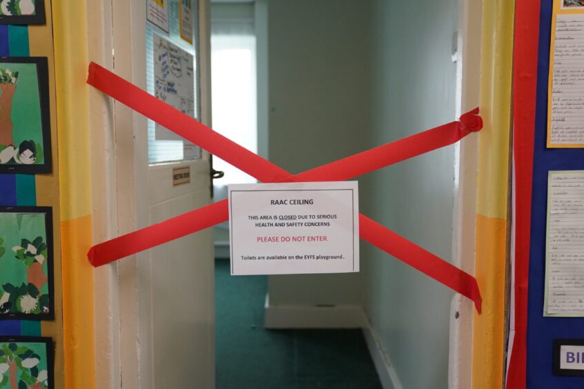 taped off section with sign saying 'RAAC ceiling, this area is closed due to serious health and safety concerns, please do not enter'.