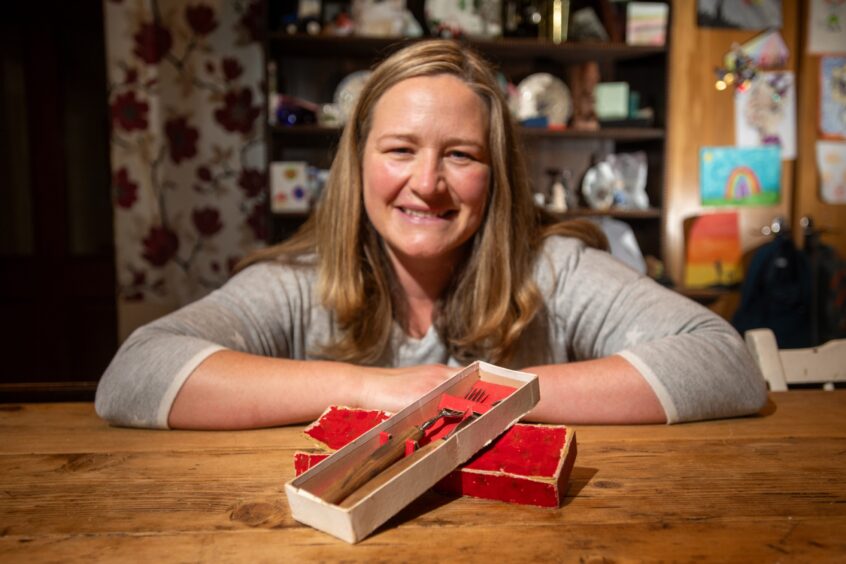 Image shows Catriona Steven with her Everyday Heirloom, her own steak knife and fork set. Catriona is seated at her kitchen table with the cutlery in front of her in its original red display box.
