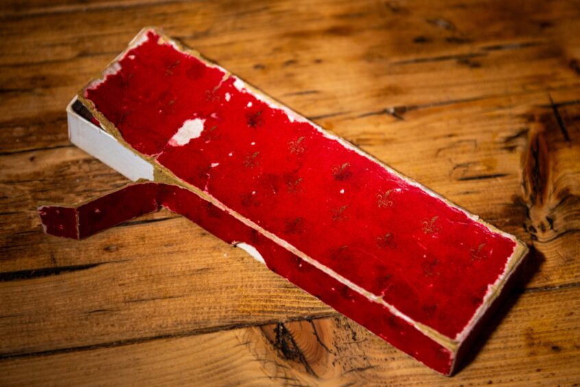 Image shows Catriona Steven's Everyday Heirloom, a red presentation case containing a steak knife and fork.The deep red box is worn around the edges.