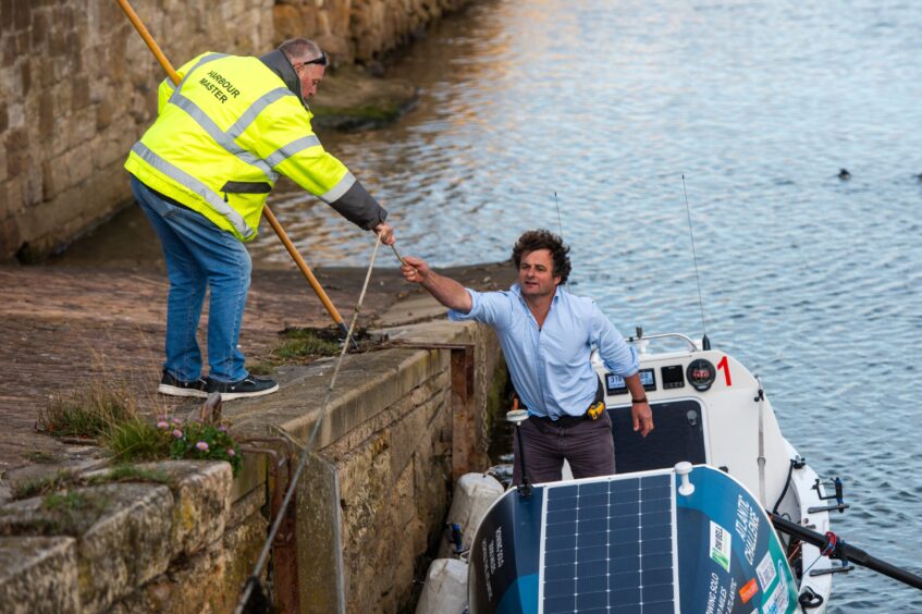 St Andrews businessman Henry Cheape as he rows ashore to showcase the Polly Anne and is welcomed by the St Andrews Harbourmaster. 
