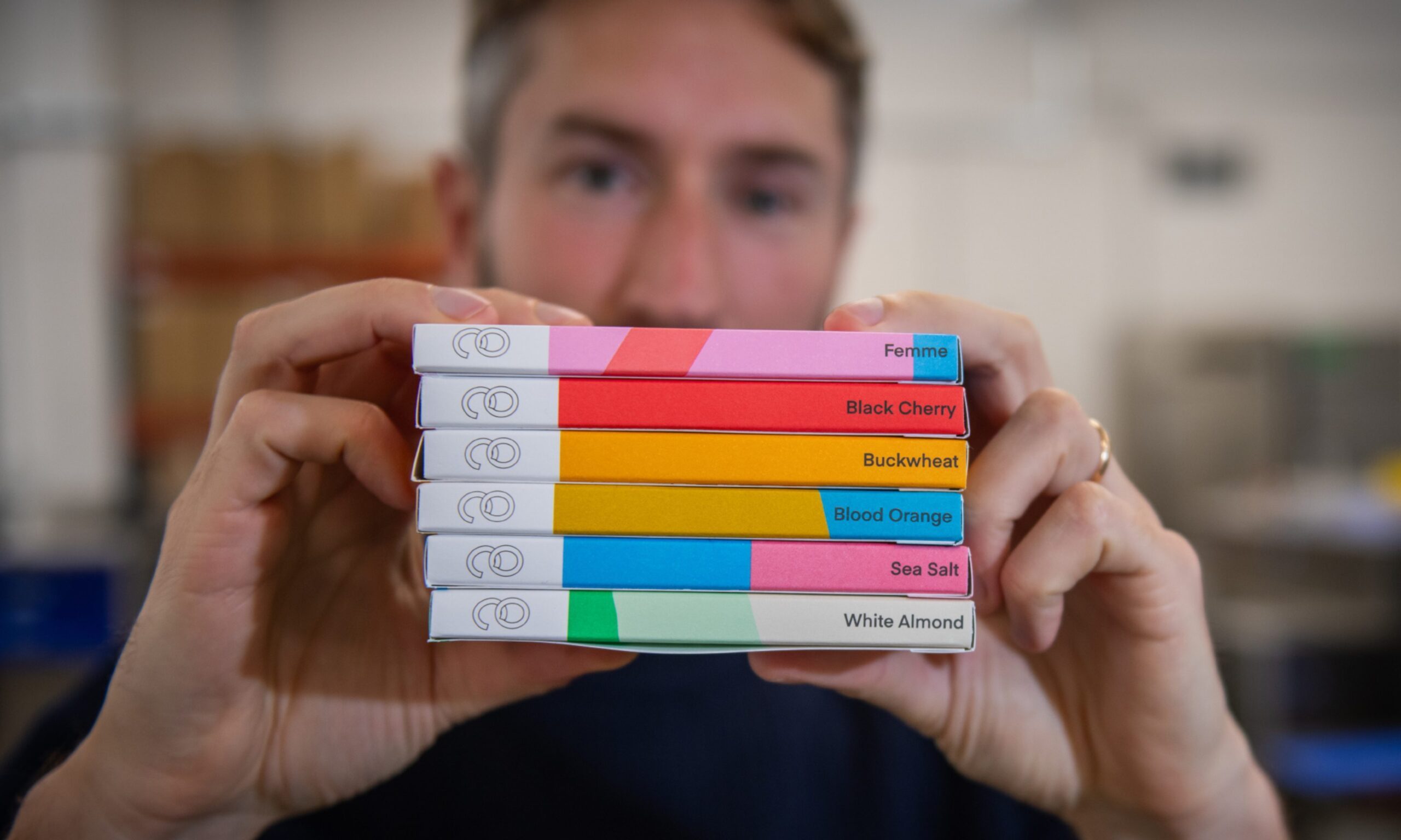 Co-founder Matt Broadbent holding up six colourful bars of Ocelot Chocolate.