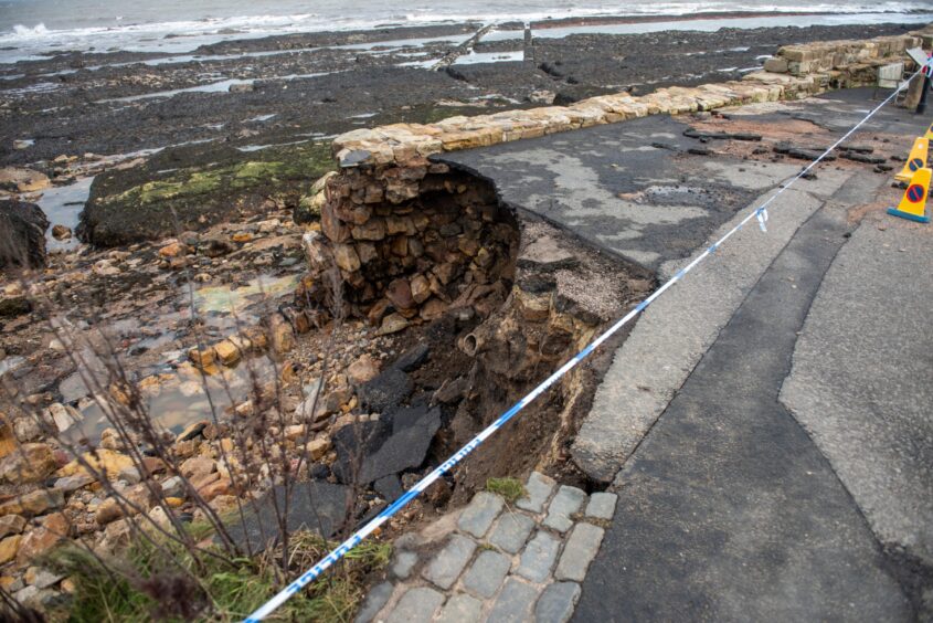 Walkers face a sheer drop at St Andrews Harbour due to storm damage. 