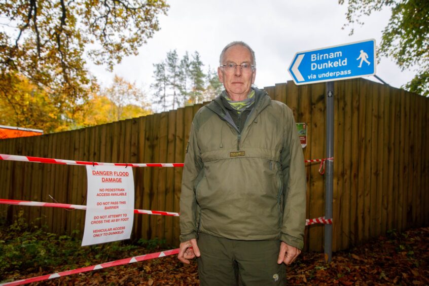 David Bee standing next to sign telling people to steer clear of the Dunkeld underpass