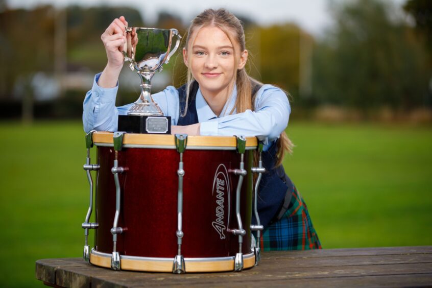 Flora McNab leaning on drum holding trophy