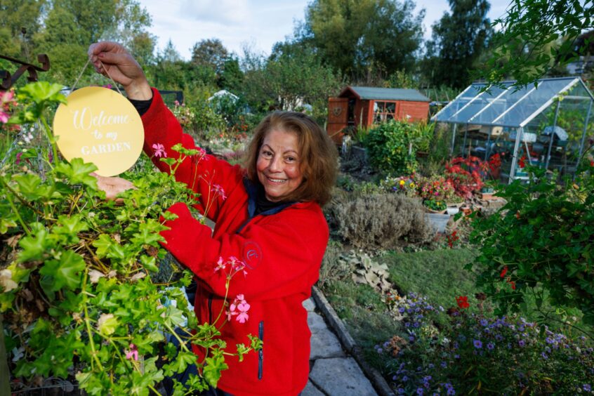 Olga Shelley holding a sign which reads 'welcome to my garden' at the Moncreiffe Island allotments