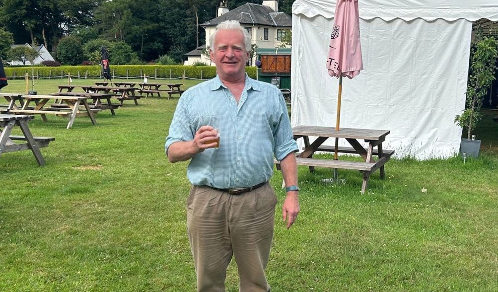 Jamie Montgomery holding glass in front of tent at Kinross beer garden