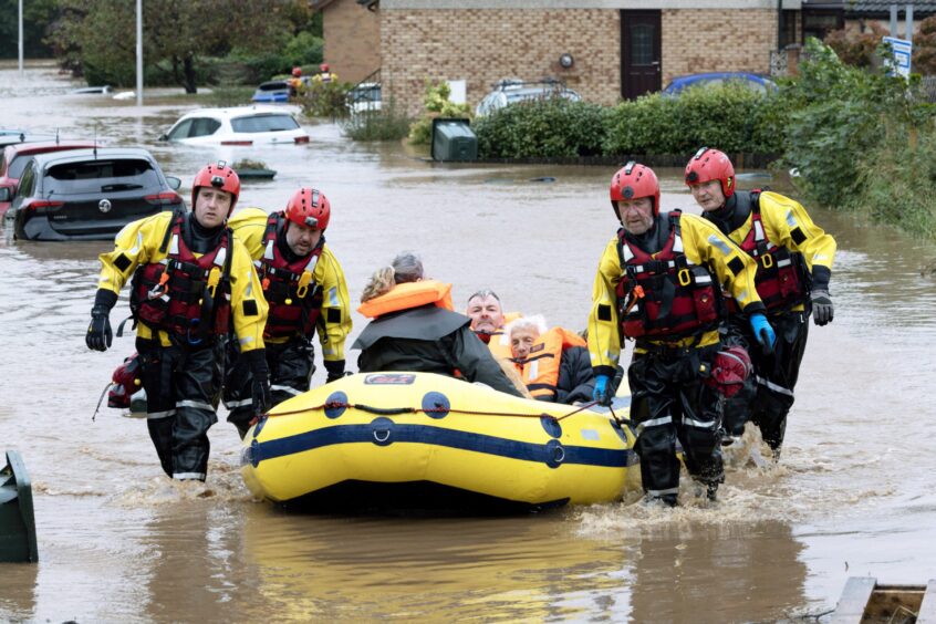 Lewis Fyall and family in rescue boat being led through flooding in Invergowrie